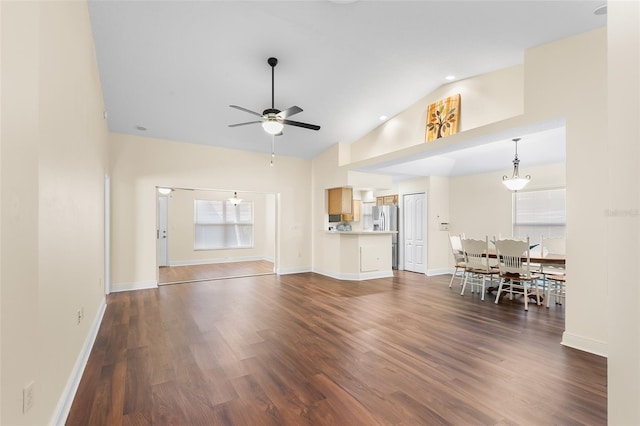 unfurnished living room featuring a healthy amount of sunlight, high vaulted ceiling, dark hardwood / wood-style floors, and ceiling fan