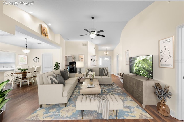 living room with dark wood-type flooring, lofted ceiling, and ceiling fan with notable chandelier