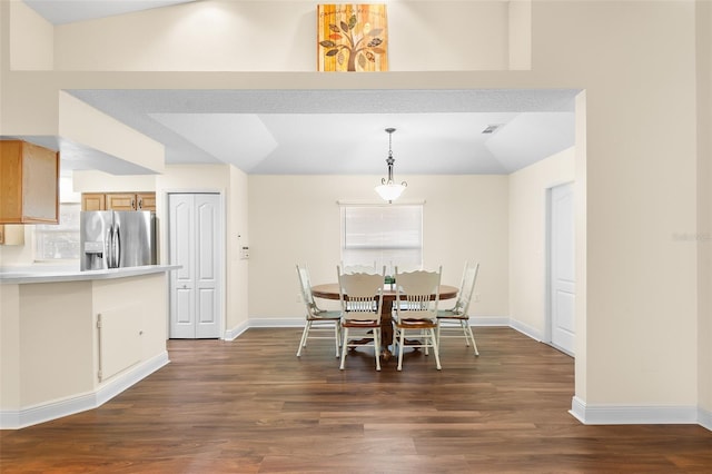 dining room with dark hardwood / wood-style floors, a textured ceiling, and vaulted ceiling