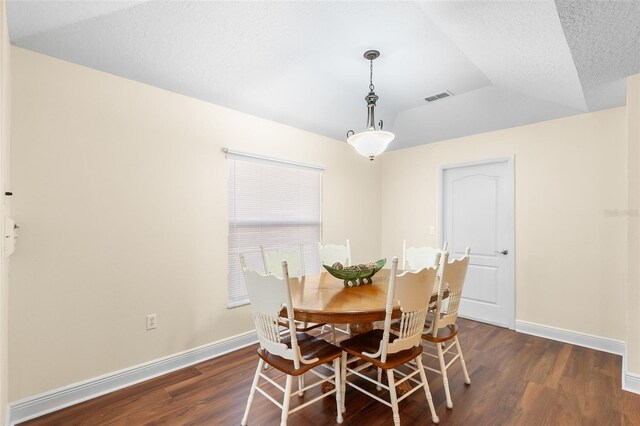 dining area with dark wood-type flooring, a textured ceiling, and vaulted ceiling