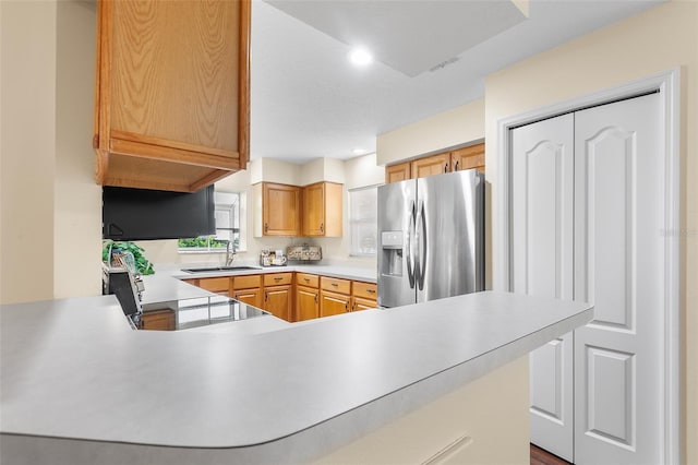 kitchen featuring kitchen peninsula, sink, black range, and stainless steel fridge with ice dispenser