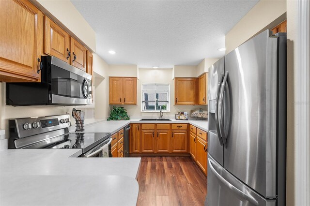 kitchen featuring stainless steel appliances, sink, kitchen peninsula, a textured ceiling, and dark wood-type flooring