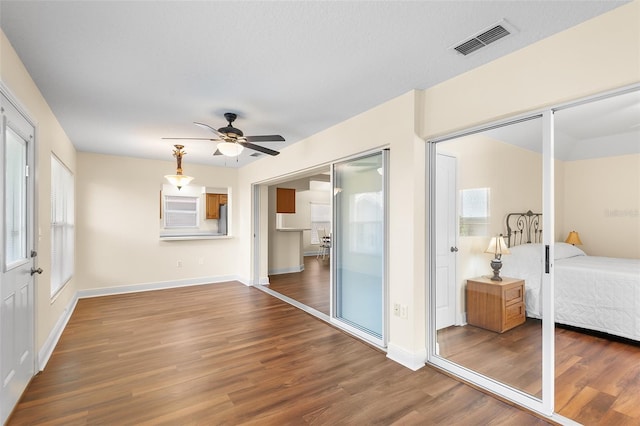 bedroom featuring ceiling fan, multiple windows, and dark hardwood / wood-style flooring