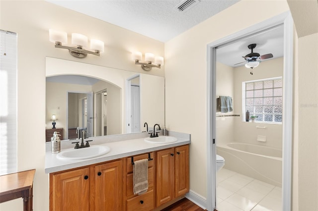 bathroom featuring vanity, a textured ceiling, tile patterned flooring, a bathing tub, and toilet