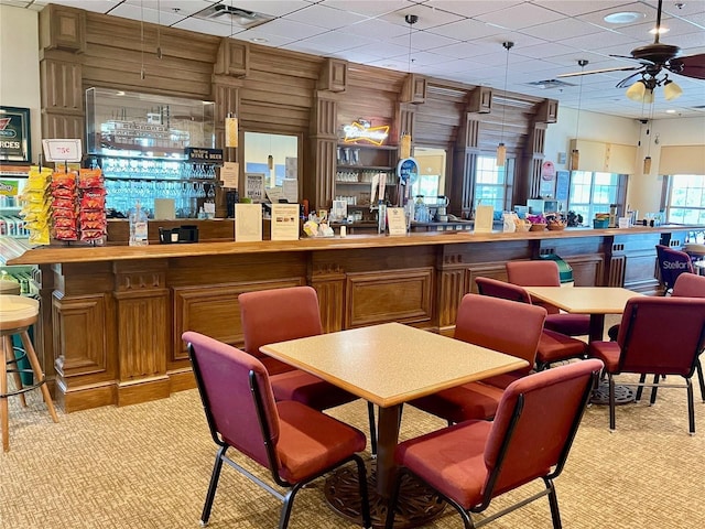 bar with wood walls, ceiling fan, and light colored carpet