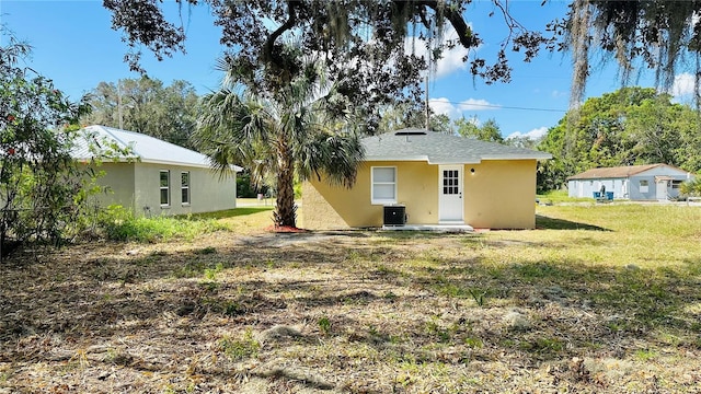 rear view of property featuring a lawn and cooling unit