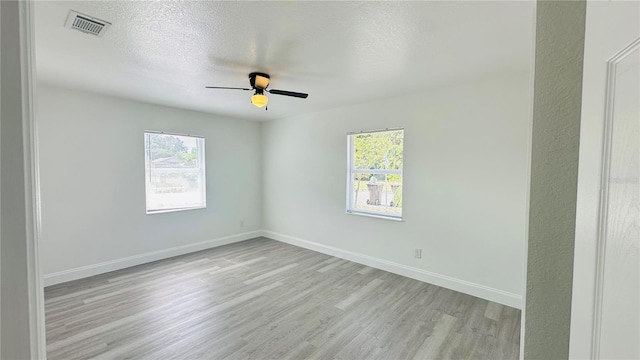 spare room with a textured ceiling, light wood-type flooring, and ceiling fan