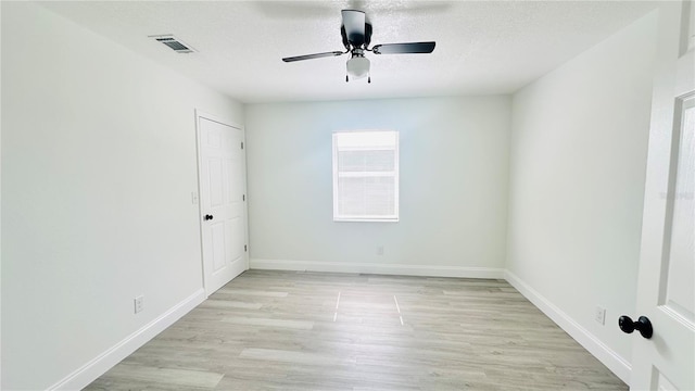 unfurnished room featuring a textured ceiling, light wood-type flooring, and ceiling fan