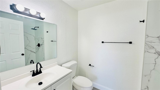 bathroom with vanity, a tile shower, and toilet