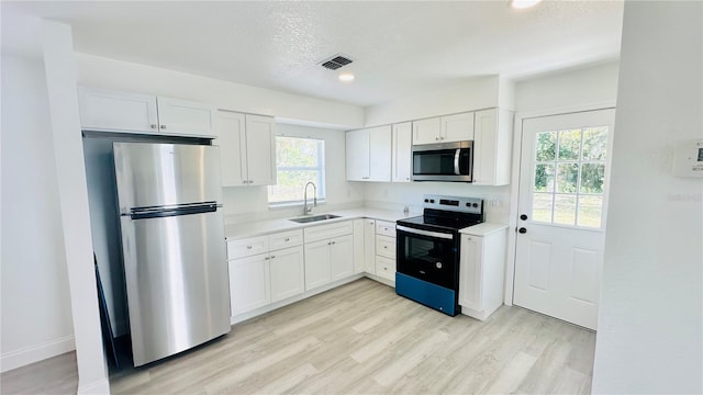 kitchen featuring appliances with stainless steel finishes, white cabinets, and sink