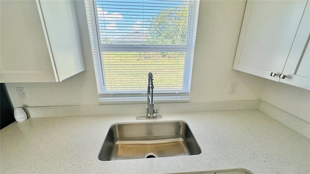 details with light stone countertops, sink, and white cabinets