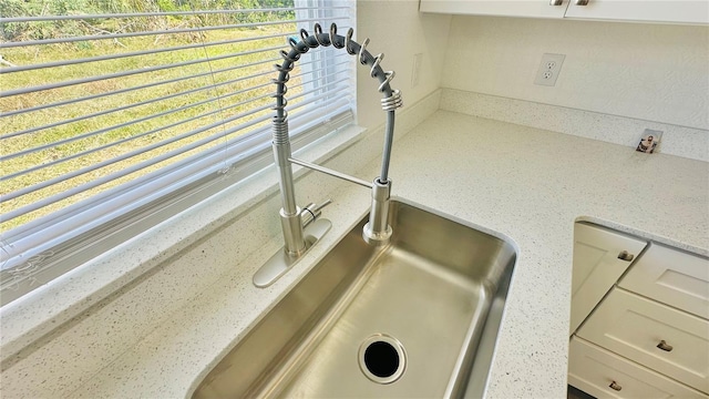 room details with light stone counters, sink, and white cabinets