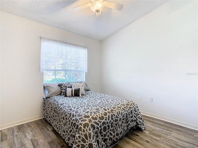 bedroom featuring ceiling fan, vaulted ceiling, wood-type flooring, and a textured ceiling