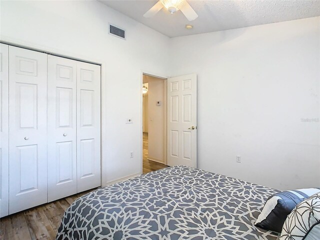 bedroom with dark hardwood / wood-style flooring, ceiling fan, and a closet