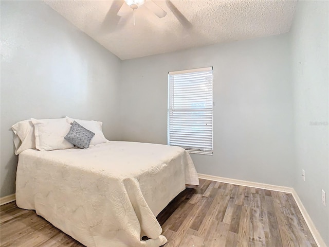 bedroom with a textured ceiling, hardwood / wood-style flooring, and ceiling fan