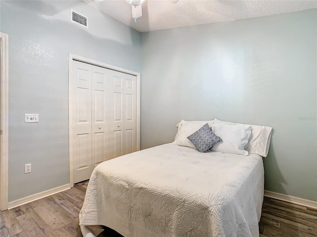 bedroom with hardwood / wood-style flooring, ceiling fan, a closet, and a textured ceiling