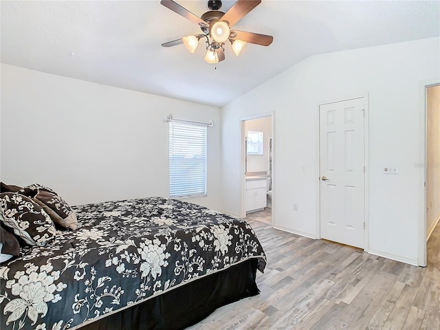 bedroom featuring ceiling fan, light hardwood / wood-style floors, vaulted ceiling, and ensuite bath