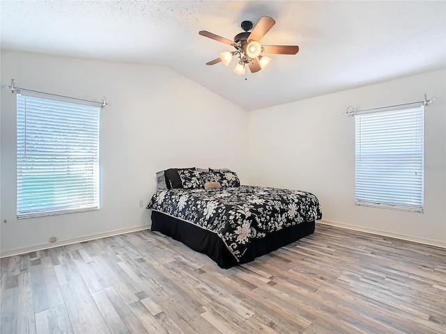 bedroom with ceiling fan, light hardwood / wood-style floors, and lofted ceiling