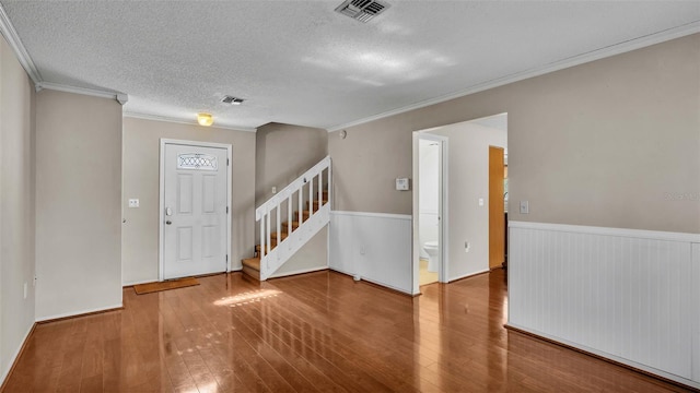 entryway with ornamental molding, a textured ceiling, and hardwood / wood-style flooring