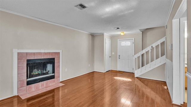 entryway featuring crown molding, a textured ceiling, wood-type flooring, and a tile fireplace