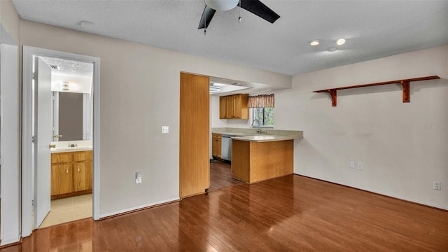 kitchen with dishwasher, a textured ceiling, kitchen peninsula, ceiling fan, and light hardwood / wood-style flooring