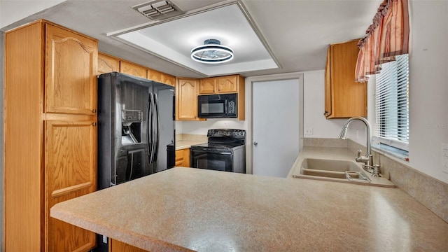 kitchen with sink, black appliances, kitchen peninsula, and a tray ceiling