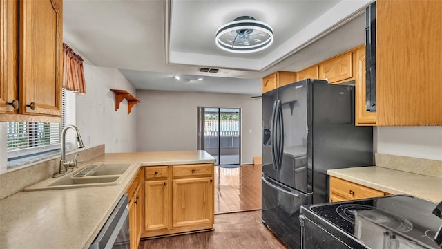 kitchen featuring sink, dishwasher, a tray ceiling, kitchen peninsula, and dark hardwood / wood-style floors