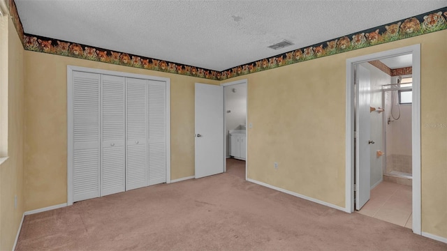 unfurnished bedroom with connected bathroom, light carpet, and a textured ceiling