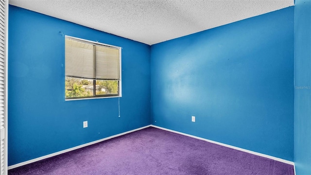 unfurnished room with dark carpet and a textured ceiling