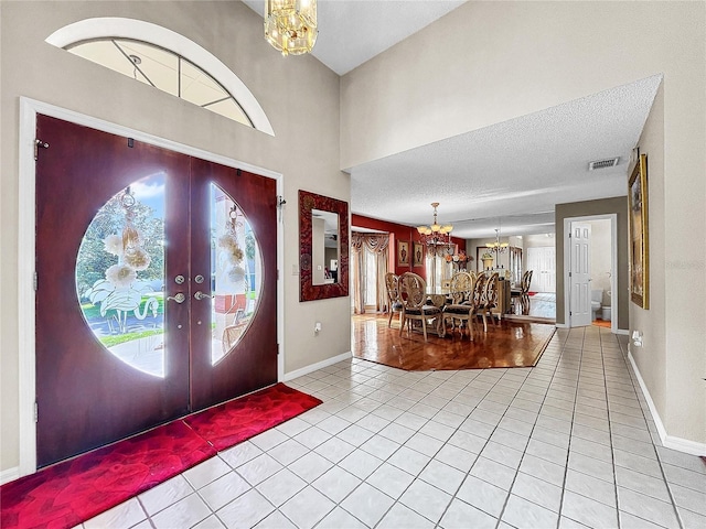 foyer entrance featuring french doors, a textured ceiling, light tile patterned flooring, and a wealth of natural light