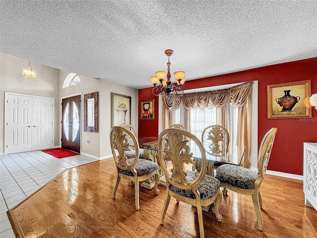 dining area with a chandelier, a textured ceiling, wood finished floors, and baseboards