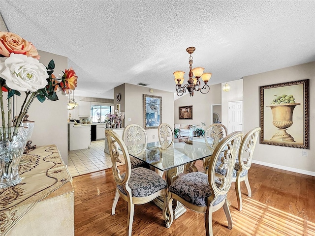 dining room featuring a notable chandelier, a textured ceiling, and light hardwood / wood-style flooring