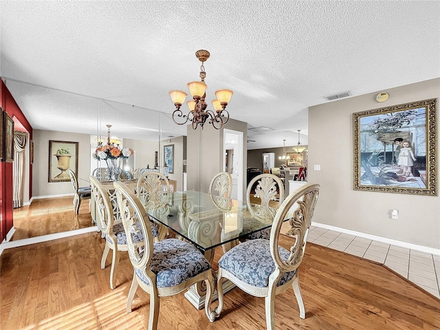 dining area with hardwood / wood-style flooring, a textured ceiling, and an inviting chandelier