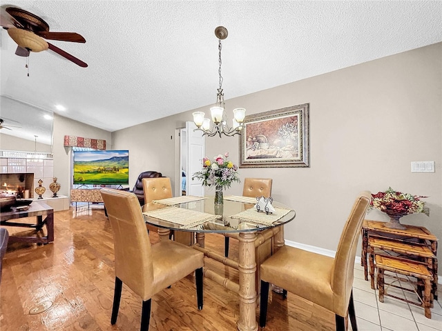 dining space featuring a textured ceiling, ceiling fan with notable chandelier, and vaulted ceiling