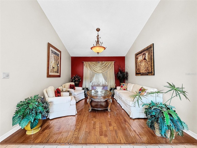 living area with vaulted ceiling, wood finished floors, and baseboards