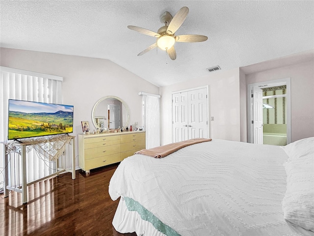 bedroom featuring a closet, dark wood-type flooring, vaulted ceiling, ensuite bathroom, and ceiling fan