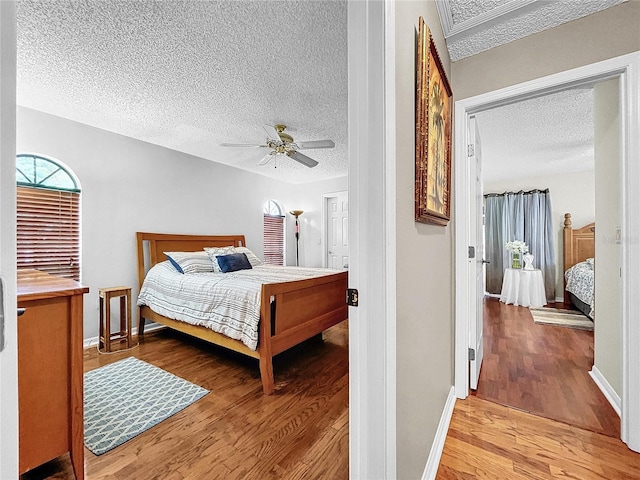 bedroom featuring a textured ceiling, ceiling fan, light wood finished floors, and baseboards