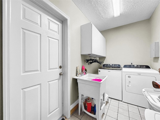 washroom featuring cabinet space, a textured ceiling, washing machine and clothes dryer, and light tile patterned flooring