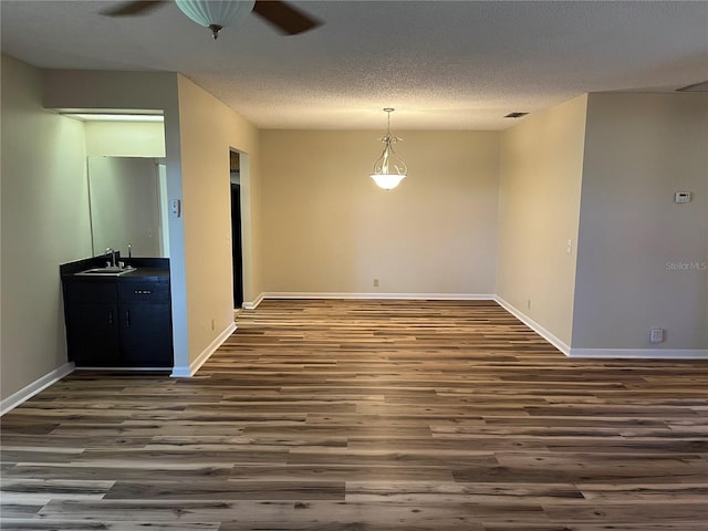 empty room with ceiling fan, a textured ceiling, sink, and dark hardwood / wood-style floors