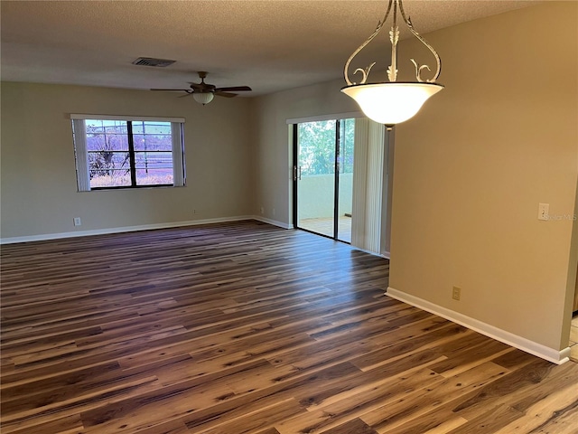 empty room with dark hardwood / wood-style floors, ceiling fan, a textured ceiling, and a wealth of natural light