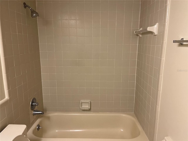 bathroom with toilet and tiled shower / bath