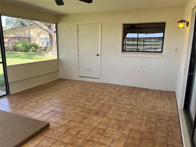 unfurnished sunroom with ceiling fan