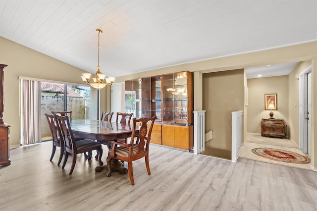 dining room featuring lofted ceiling, light wood-type flooring, and a chandelier