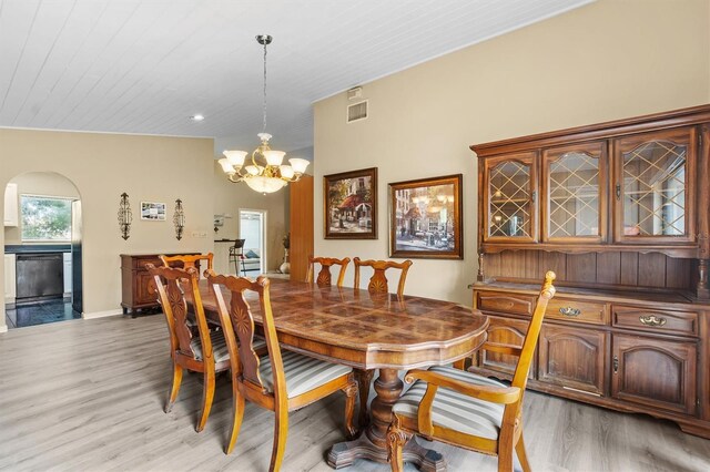 dining space with lofted ceiling, a chandelier, and light hardwood / wood-style flooring