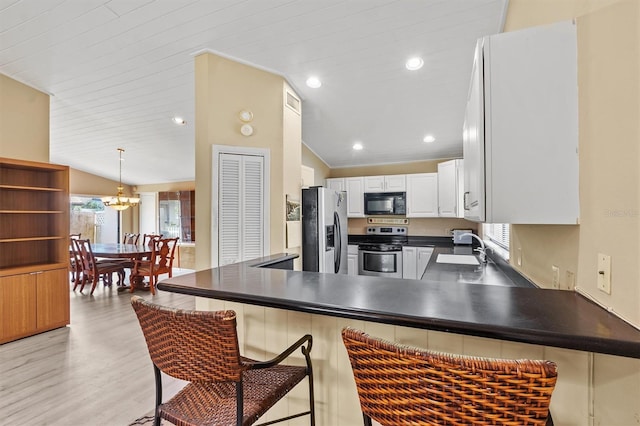 kitchen featuring white cabinetry, appliances with stainless steel finishes, a kitchen bar, and kitchen peninsula