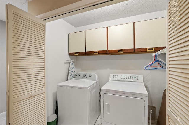 laundry area featuring cabinets, separate washer and dryer, and a textured ceiling