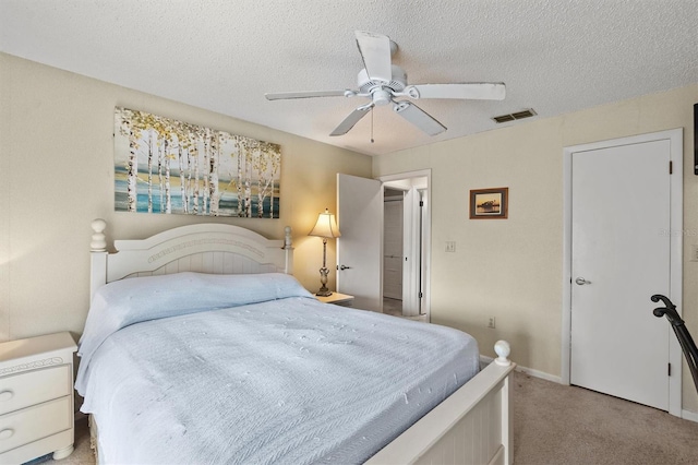 bedroom with ceiling fan, light colored carpet, and a textured ceiling