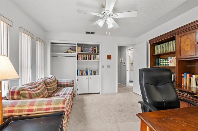 office featuring ceiling fan, light carpet, and a textured ceiling