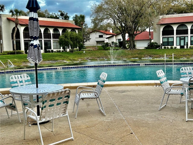 view of pool with a patio and a lawn