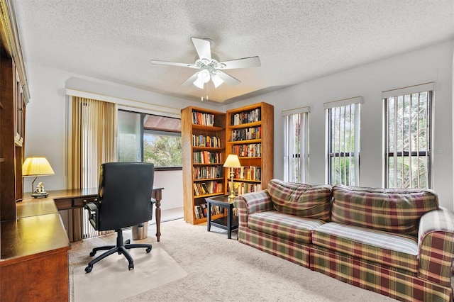 carpeted home office featuring ceiling fan and a textured ceiling